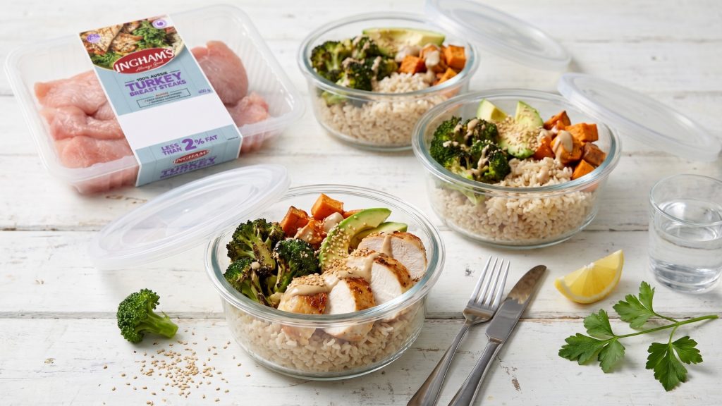 Three glass meal prep containers filled with sliced Ingham's turkey breast steaks, brown rice, roasted broccoli, sweet potato and avocado
